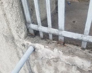 Verwittertes Metallgitter auf rissigem Betonrand